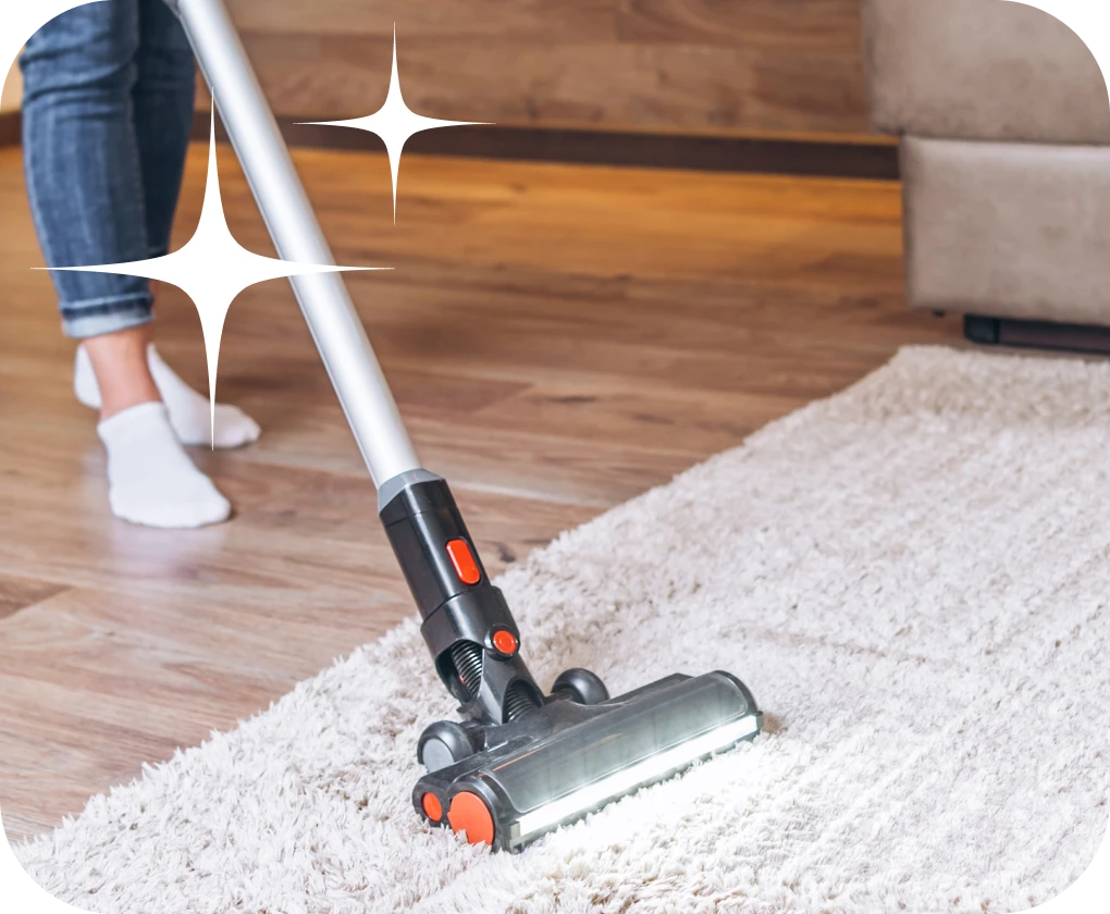 Homeowner vacuuming area rug with stick vacuum | Lloyd's Carpets & Draperies