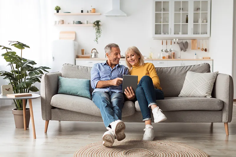 Couple reading tablet on couch | Lloyd's Carpets & Draperies